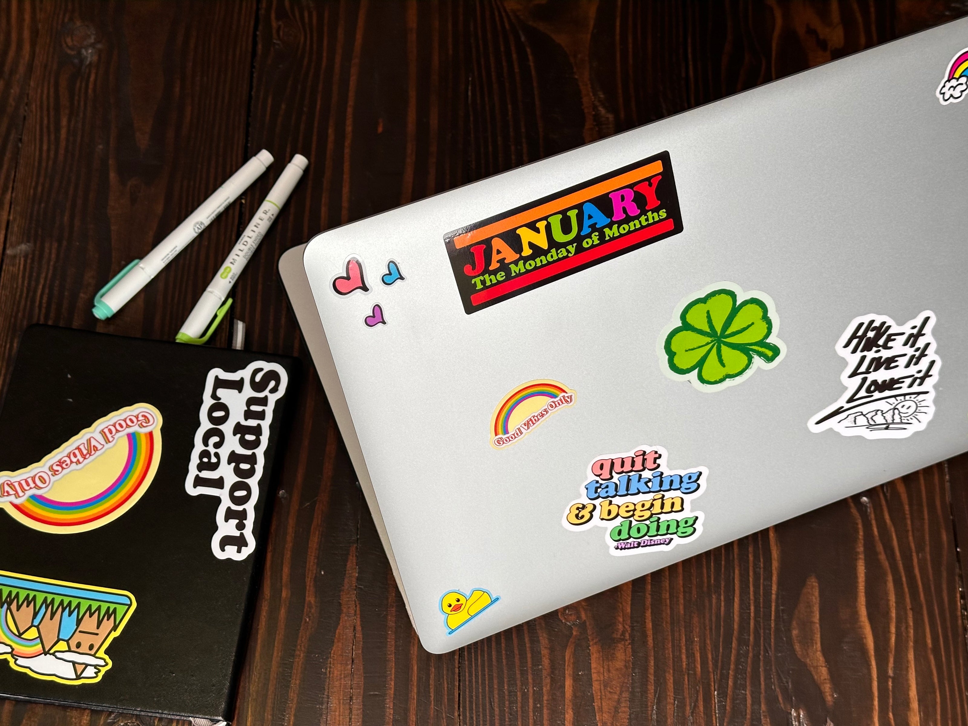 Laptop with various colorful stickers on a wooden surface